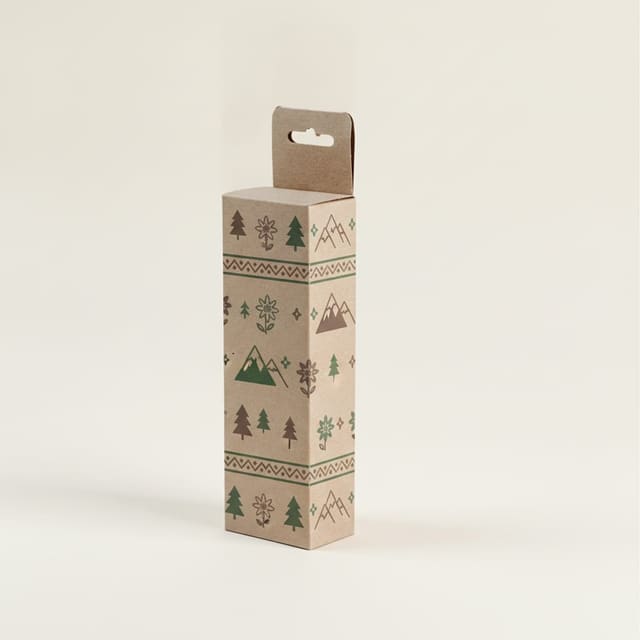 Caja alargada en cartulina kraft decorada con una cenefa de abetos y montañas en verde