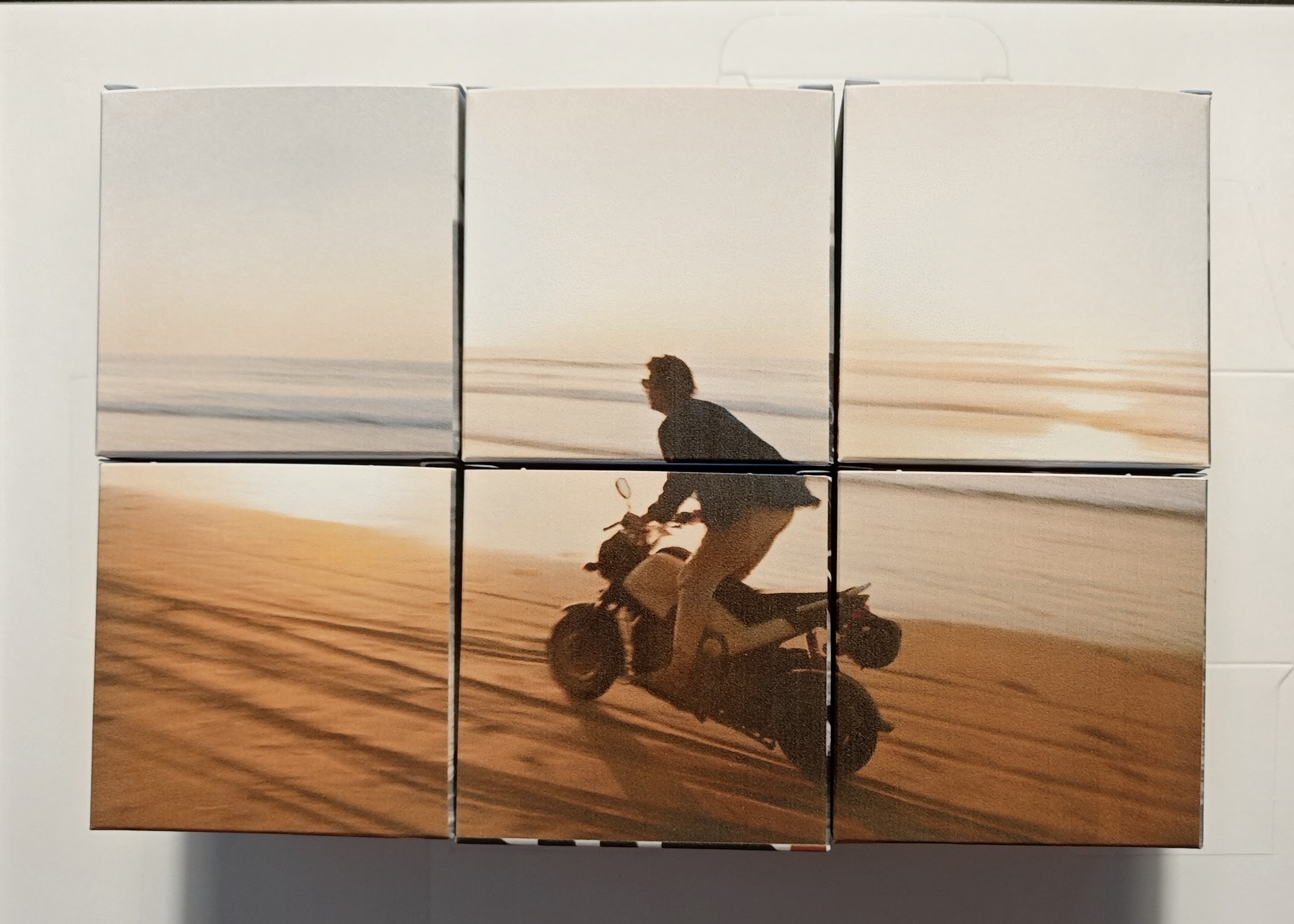 Las mismas 6 cajas Kajica giradas mostrando otra foto completa, una moto en la playa al atardecer